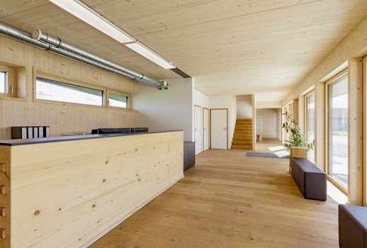 Empfangsbereich des Rehklau Firmen-Gebäudes mit Holzvertäfelung und Rehklau-Design. Der Raum ist hell und mit großen Fenstern ausgestattet, die viel natürliches Licht hereinlassen.