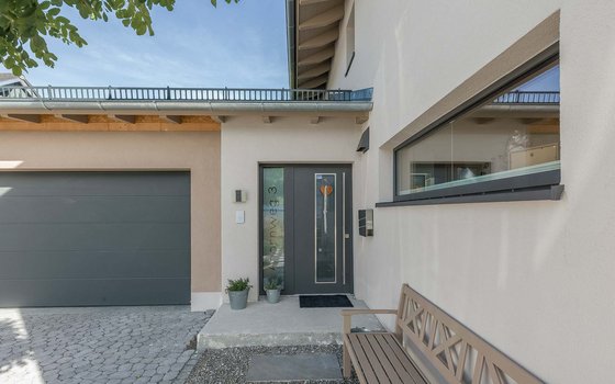 Hauseingang mit Garage eines modernen weißten Hauses mit grauer Türe und Tor
