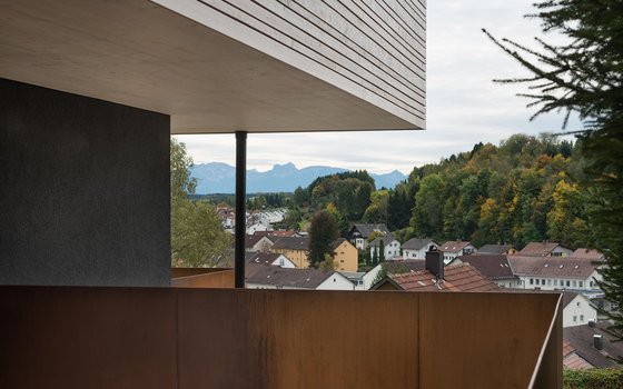 Blick von einer modernen Terrasse auf eine Stadt mit Bergkulisse im Hintergrund.