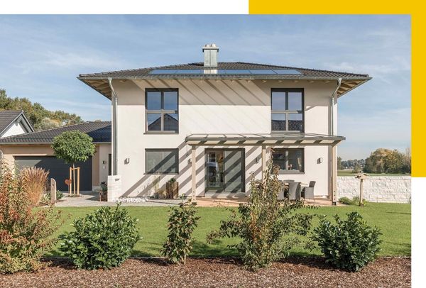 Ein modernes Haus mit hellem Putz und einem Schrägdach. Der Garten ist gepflegt und der Eingangsbereich hat eine Überdachung mit Schattenwirkung.