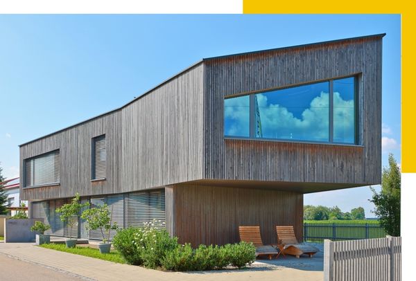 Modernes Rehklau Holzgebäude mit minimalistischer Architektur Außenansicht eines modernen, zweistöckigen Holzgebäudes von Rehklau mit großen Fenstern und einer auffälligen gelben Ecke im Hintergrund. Das Gebäude ist von Pflanzen umgeben und hat ein minimalistisches Design.